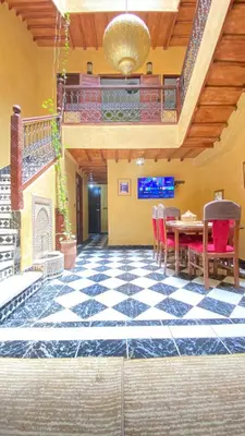 a room with a table and chairs and a checkerboard floor at Riyad Entier Avec piscine Red Moon Kech in Marrakech