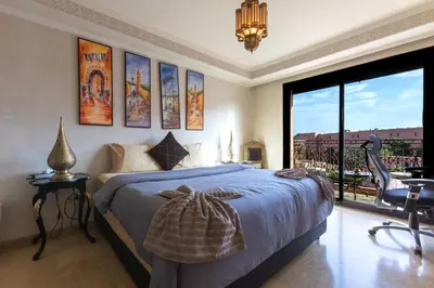 a bedroom with a bed and a chair and a window at Superbe appartement calme Hivernage in Marrakech