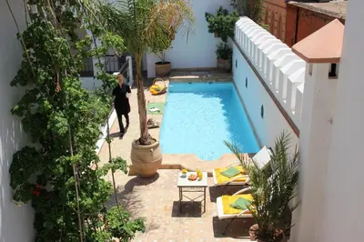 a man standing next to a swimming pool in a building at Riad Clémentine in Marrakech