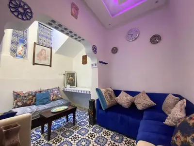 a living room with a blue couch and clocks on the wall at Dwira in Marrakech