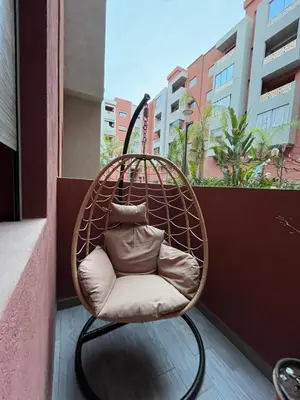 a rattan chair sitting on a balcony at ASAMA appartement avec piscine et terrasse, proche du centre in Marrakech