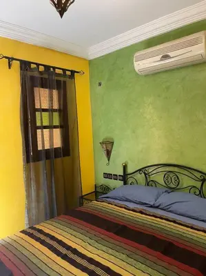 a bedroom with a bed with yellow walls and a window at Dxb Riad 4 suites in Marrakech