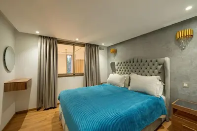 a bedroom with a bed with blue sheets and a window at Duplex Haut Standing 24 in Marrakech
