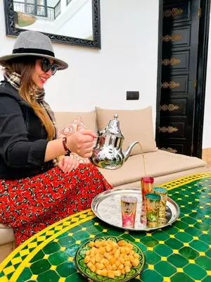 a woman sitting at a table with a tea pot at Dar Nossa in Marrakech
