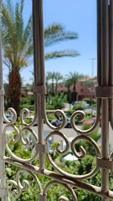 a metal fence with a palm tree in the background at Riad à Marrakech dans la Résidence Touristique Al Qaria Assiyahia in Marrakech