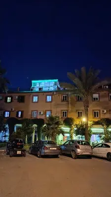 a building with cars parked in a parking lot at night at Riad à Marrakech dans la Résidence Touristique Al Qaria Assiyahia in Marrakech