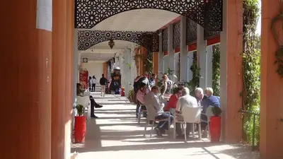 a group of people sitting in chairs on a sidewalk at Riad à Marrakech dans la Résidence Touristique Al Qaria Assiyahia in Marrakech