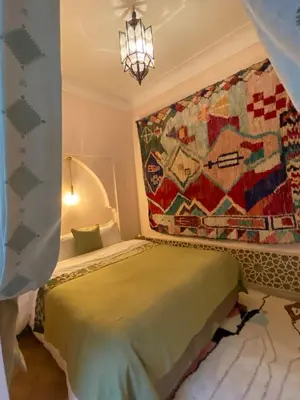 a bedroom with a bed with a tapestry on the wall at Riad Dar Adal exclusivité 2 à 6 personnes petit déjeuner compris place jemaa El fna in Marrakech