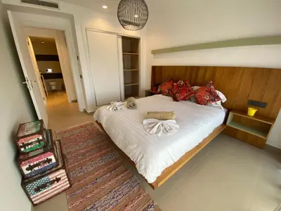 a bedroom with a large bed with white sheets and red pillows at Luxueux Appart Hivernage avec vue sur L''Atlas in Marrakech