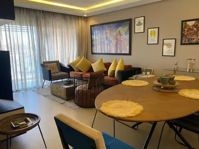 a living room with a table and chairs at Luxueux Appart Hivernage avec vue sur L''Atlas in Marrakech