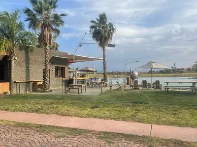 a patio with tables and palm trees next to a body of water at appartement dans Jardin de l'atlas in Marrakech
