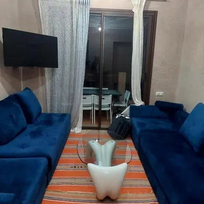 a living room with blue couches and a tv at appartement dans Jardin de l'atlas in Marrakech