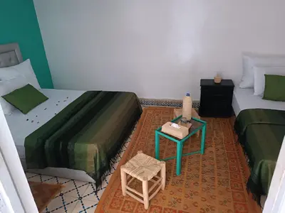 a room with two beds and a table with a stool at marrakesh riad in Marrakech