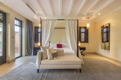 a bedroom with a white bed and a chair at Luxury Villa GoldPalm Marrakech in Marrakech