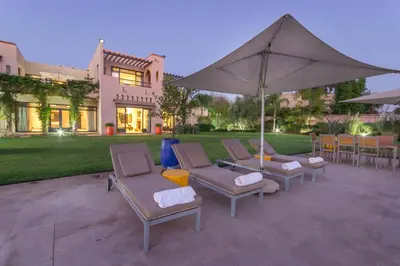 a patio with chairs and a table with an umbrella at Luxury Villa GoldPalm Marrakech in Marrakech