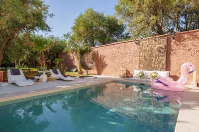 a swimming pool with a pink flamingo in the water at Villa Souad 5 Suites - Parking & Piscine Privée in Marrakech