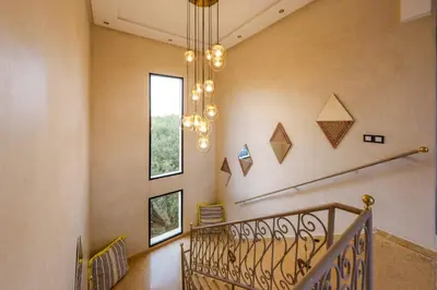 a hallway with a staircase with a chandelier at Villa Souad 5 Suites - Parking & Piscine Privée in Marrakech