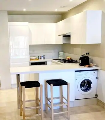 a kitchen with a counter and a washing machine at Appartement raffiné idéalement situé avec piscine in Marrakech