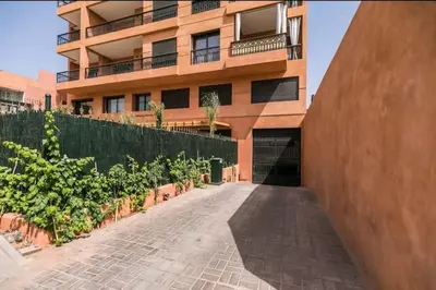 a building with a courtyard with plants in front of it at Appartement raffiné idéalement situé avec piscine in Marrakech