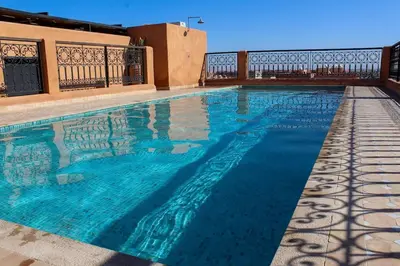 a swimming pool with blue water in front of a building at Appartement raffiné idéalement situé avec piscine in Marrakech