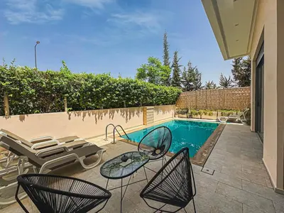 a patio with chairs and a swimming pool at Villa LEONARDO Piscine & Rooftop Terrase in Marrakech