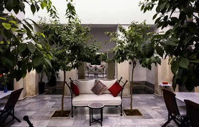 a white couch sitting in a courtyard with trees at Riad Sapphire & Spa in Marrakech