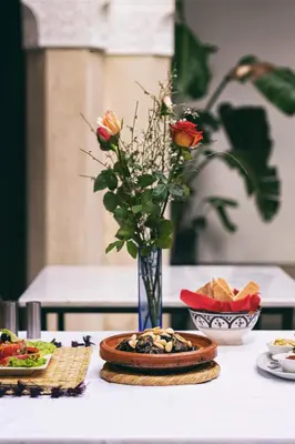 a table with a plate of food and a vase with roses at Riad Sapphire & Spa in Marrakech