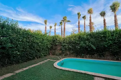 a swimming pool in a yard with palm trees at The Majestic Marrakesh Villa 2 in Marrakech