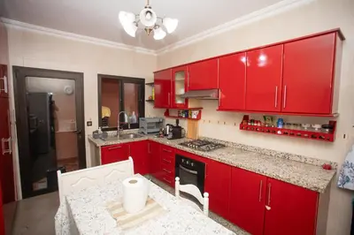 a red kitchen with red cabinets and a table at Apartamento Residencia Kasbah de Marrakech 1 Gueliz in Marrakech