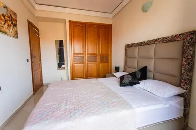 a bedroom with a large white bed with a wooden headboard at A stunning 2 bedroom Hivernage in Marrakech