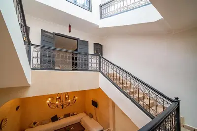 a room with a staircase with a couch and a chandelier at Riad Résidence Al Qaria Assiyahia Riad 22 in Marrakech