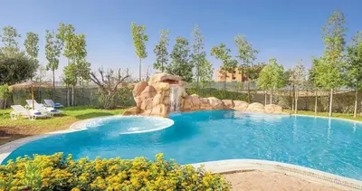 a large swimming pool with a waterfall in a yard at Vizir Center Appartements in Dar Caïd Layadi