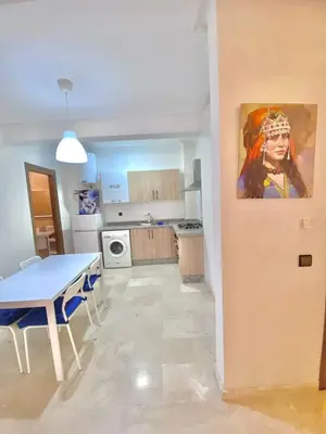 a kitchen with a table and a painting on the wall at Appartement avec piscine en face à la gare gueliz in Marrakech