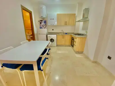 a kitchen with a white table and a white refrigerator at Appartement avec piscine en face à la gare gueliz in Marrakech