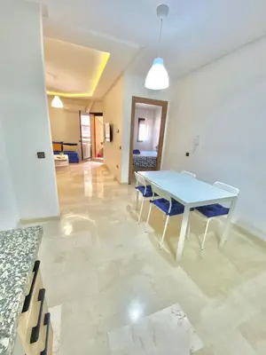 a dining room with a table and blue chairs at Appartement avec piscine en face à la gare gueliz in Marrakech
