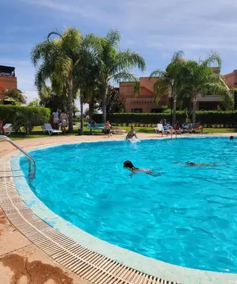 a person swimming in a large blue swimming pool at Tres joli Apparemment atlas golf rosort by marwa € ilyes in Marrakech
