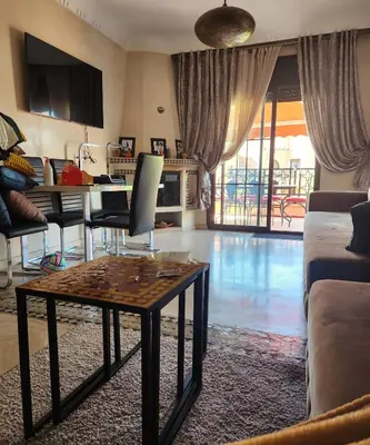 a living room with a table and a pool at Tres joli Apparemment atlas golf rosort by marwa € ilyes in Marrakech