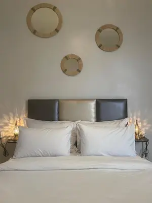 a bed with white pillows and two mirrors on the wall at Riad Hanya in Marrakech