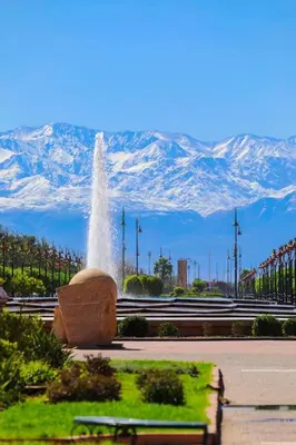a fountain in a park with mountains in the background at Riad Majestic Marrakech in Marrakech