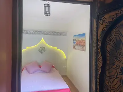 a small bedroom with a bed with pink pillows at Le riad de Salima, Noor Es Saadi design in Marrakech