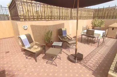 a patio with chairs and a table and an umbrella at RIAD PRIVATISÉ 3 Chambres 6 Personnes Place Jemma El Fna in Marrakech