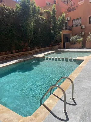 a large swimming pool with a handrail in front of a building at Bel appartement en centre-ville avec piscine in Marrakech