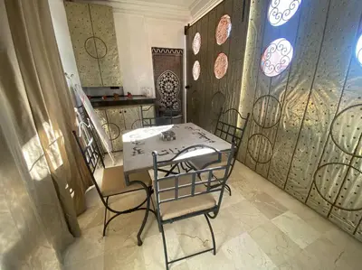a table and chairs in a room with a wall at Bel appartement en centre-ville avec piscine in Marrakech