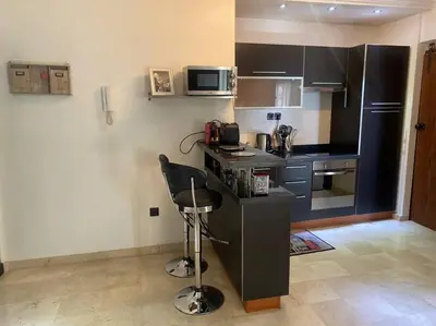 a small kitchen with a counter and a chair in it at Bel appartement en centre-ville avec piscine in Marrakech