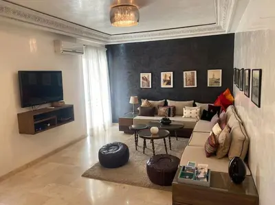 a living room with a couch and a tv at Bel appartement en centre-ville avec piscine in Marrakech