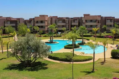 an apartment complex with a swimming pool in a park at BEL APPART FONCTIONNEL PRESTIGIA GOLF MARRAKECH in Marrakech