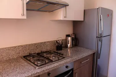 a kitchen with a stove and a refrigerator at BEL APPART FONCTIONNEL PRESTIGIA GOLF MARRAKECH in Marrakech