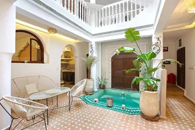 a pool in the middle of a room with a table and chairs at Riad El Khir en centre ville rooftop et bassin in Marrakech