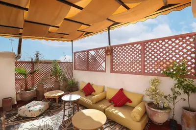 a couch under an umbrella on a patio at Riad El Khir en centre ville rooftop et bassin in Marrakech