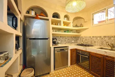 a kitchen with a stainless steel refrigerator and shelves at Riad El Khir en centre ville rooftop et bassin in Marrakech